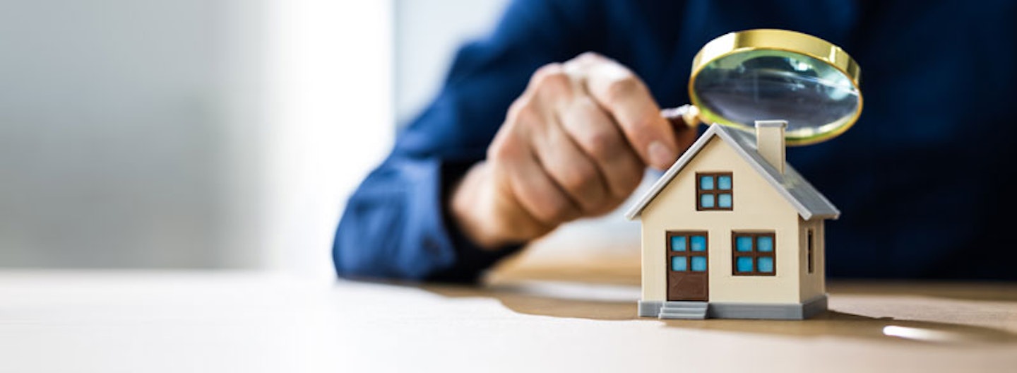 inspecting a model house with a magnifying glass
